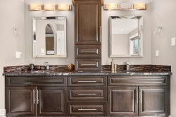 Dual vanity featuring dark wood cabinetry, a dark stone countertop, and mosaic tile backsplash - 