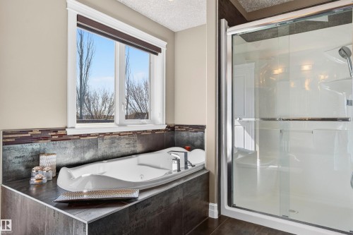 Built-in soaking tub with a tiled surround, framed window, and a glass-enclosed shower with a handheld shower fixture - 1254 Adamson Drive, Edmonton, AB - Indoor Photo Showing Bathroom