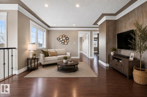 Spacious living area featuring rich wood-finish flooring, recessed lighting, and large windows with white trim - 1254 Adamson Drive, Edmonton, AB - Indoor Photo Showing Living Room