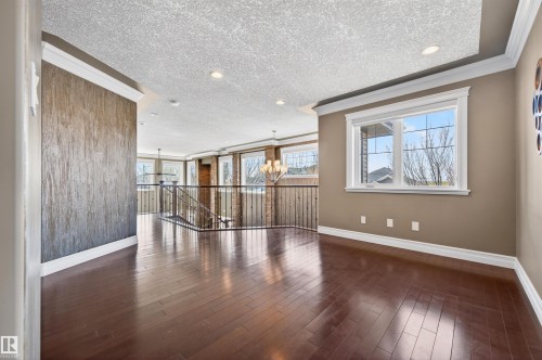 Open interior space featuring rich wood-finish flooring, a decorative textured accent wall, and crown molding - 1254 Adamson Drive, Edmonton, AB - Indoor Photo Showing Other Room