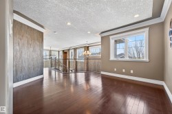 Open interior space featuring rich wood-finish flooring, a decorative textured accent wall, and crown molding - 