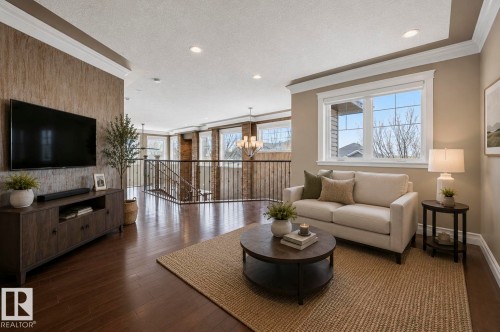 Spacious living area featuring rich wood-finish flooring, a contemporary window with grid panes, recessed lighting, and crown molding - 1254 Adamson Drive, Edmonton, AB - Indoor Photo Showing Living Room
