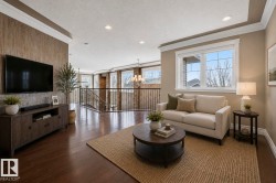 Spacious living area featuring rich wood-finish flooring, a contemporary window with grid panes, recessed lighting, and crown molding - 