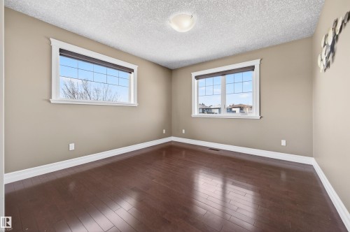 Room featuring wood-finish flooring, two large windows with white trim, and neutral-toned walls - 1254 Adamson Drive, Edmonton, AB - Indoor Photo Showing Other Room