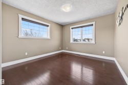 Room featuring wood-finish flooring, two large windows with white trim, and neutral-toned walls - 