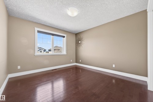 Spacious room with dark wood-finish flooring, neutral wall color, and white baseboards - 1254 Adamson Drive, Edmonton, AB - Indoor Photo Showing Other Room