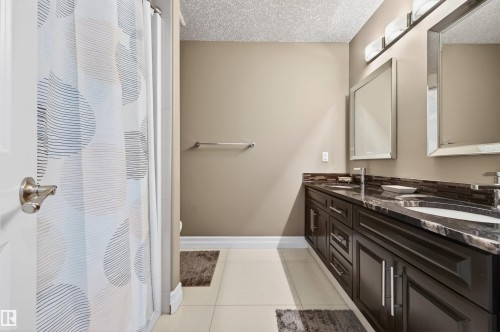 Double vanity with dark wood cabinetry, integrated sinks, and stone countertops - 1254 Adamson Drive, Edmonton, AB - Indoor Photo Showing Bathroom