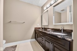 Dual sink vanity featuring dark wood cabinetry, a dark stone countertop, and two undermount sinks - 