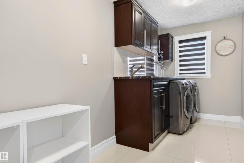 Dedicated laundry space featuring dark wood cabinetry, a sink with a faucet, and a countertop - 1254 Adamson Drive, Edmonton, AB - Indoor Photo Showing Laundry Room