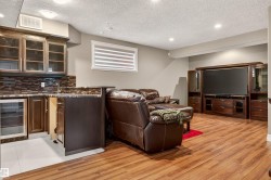 Entertainment area featuring wood-finish flooring, a built-in wet bar with a beverage cooler, and recessed lighting - 