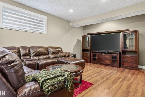 Entertainment area featuring wood-finish flooring, a built-in media center with glass-front cabinets, recessed lighting, and a window with blinds - 1254 Adamson Drive, Edmonton, AB - Indoor