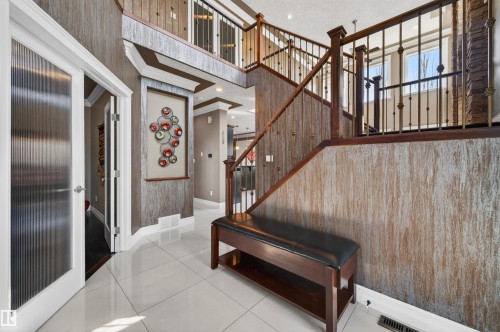 Two-story foyer featuring bright tile flooring, a dark wood-finish staircase with ornate metal balusters, textured wall finishes, and a second-story landing - 1254 Adamson Drive, Edmonton, AB - Indoor Photo Showing Other Room