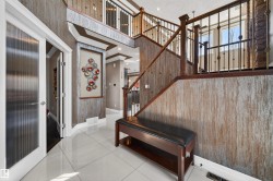 Two-story foyer featuring bright tile flooring, a dark wood-finish staircase with ornate metal balusters, textured wall finishes, and a second-story landing - 