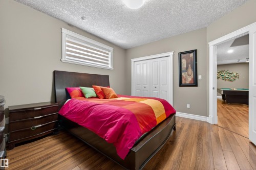 Bedroom featuring wood-finish flooring, a double-door closet, and a window with horizontal blinds - 1254 Adamson Drive, Edmonton, AB - Indoor Photo Showing Bedroom
