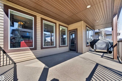 Covered exterior patio featuring a durable concrete surface, vinyl siding, and white-framed windows - 1254 Adamson Drive, Edmonton, AB - Outdoor With Deck Patio Veranda With Exterior