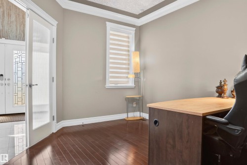 Spacious room with dark wood-finish flooring, light tan walls, and a window featuring horizontal blinds - 1254 Adamson Drive, Edmonton, AB - Indoor