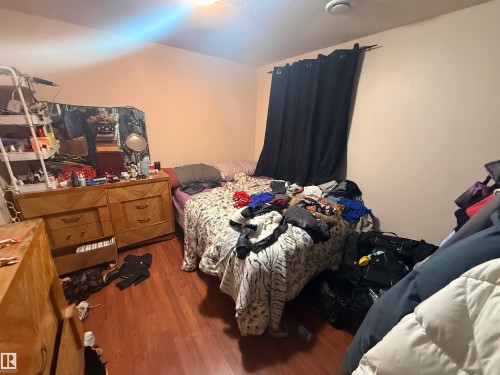 This bedroom features wood flooring, neutral colored walls, and a window with dark curtains - 10545 67 Avenue, Edmonton, AB - Indoor
