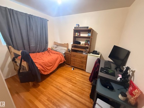 This room features hardwood flooring, a window with curtains, and light-colored walls - 10545 67 Avenue, Edmonton, AB - Indoor Photo Showing Bedroom