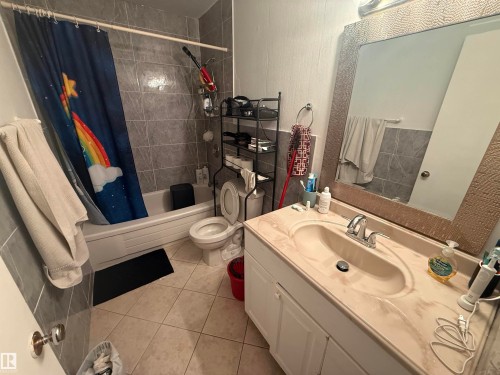 Bathroom featuring a tiled shower and bathtub, a toilet, a vanity with an integrated sink, and a large framed mirror - 10545 67 Avenue, Edmonton, AB - Indoor Photo Showing Bathroom