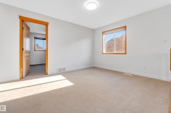 Carpeted room featuring a large window with a wood-finish frame, a mountain backdrop, a flush-mount ceiling light fixture, a wood-finish door, and white baseboards - 