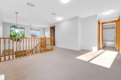 Upper-level landing featuring light-toned carpet, recessed lighting, and a wooden baluster railing - 