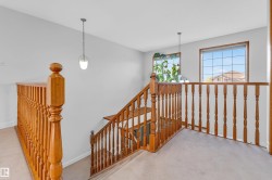 Upper-level landing featuring wood balusters and two pendant light fixtures - 
