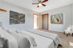 Carpeted bedroom featuring light-toned walls, a brown paneled door, a bi-fold closet door, and a ceiling fan with integrated lighting - 