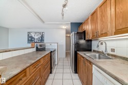 Kitchen featuring wood cabinetry, stainless steel sink with pull-down faucet, white tiled backsplash, and neutral countertops - 