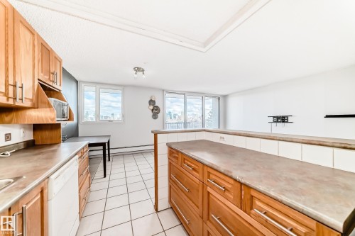 Kitchen featuring wood cabinetry, integrated dishwasher, and tile flooring - 405 10135 Saskatchewan Drive Nw, Edmonton, AB - Indoor Photo Showing Kitchen