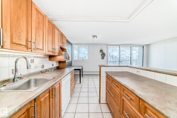 Kitchen featuring wood cabinetry, white tile backsplash, a stainless steel sink, and a white dishwasher - 