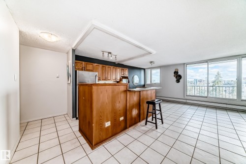 Open-concept living area with white square tile flooring and large sliding glass doors leading to a balcony - 405 10135 Saskatchewan Drive Nw, Edmonton, AB - Indoor Photo Showing Kitchen