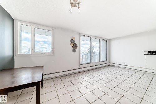Spacious room featuring white tile flooring, ample natural light from multiple windows, and a sliding glass door - 405 10135 Saskatchewan Drive Nw, Edmonton, AB - Indoor Photo Showing Other Room