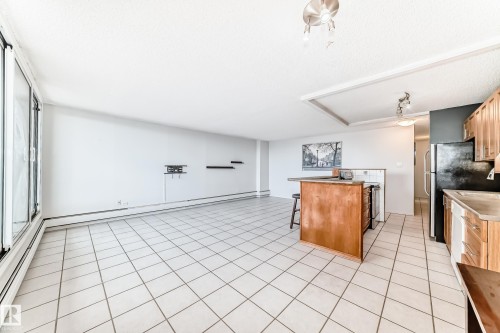 Bright living area featuring large windows, white ceramic tile flooring, a breakfast bar, wood-finish cabinetry, and recessed lighting - 405 10135 Saskatchewan Drive Nw, Edmonton, AB - Indoor Photo Showing Kitchen