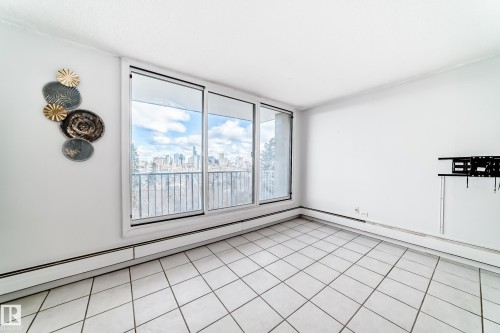 Bright interior featuring expansive windows with city scenery, tile flooring, and a balcony with metal railings - 405 10135 Saskatchewan Drive Nw, Edmonton, AB - Indoor Photo Showing Other Room