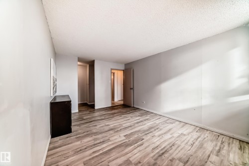 Spacious room featuring wood-finish flooring, light grey painted walls, and textured white ceilings - 405 10135 Saskatchewan Drive Nw, Edmonton, AB - Indoor Photo Showing Other Room