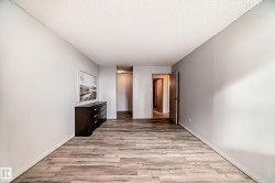 Spacious interior room featuring wood-finish flooring, light gray wall tones, white baseboards, and a textured ceiling - 