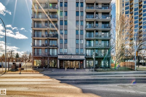 Multi-story residential building featuring a stone and stucco facade, private balconies with glass railings, and ground-level commercial or amenity spaces - 405 10135 Saskatchewan Drive Nw, Edmonton, AB - Outdoor With Facade