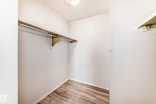 Interior closet featuring wood-finish flooring, a white clothes rod, and an upper shelf - 405 10135 Saskatchewan Drive Nw, Edmonton, AB - Indoor With Storage