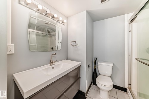 Bathroom featuring a modern vanity with integrated sink, brushed nickel faucet, and overhead bar lighting - 405 10135 Saskatchewan Drive Nw, Edmonton, AB - Indoor Photo Showing Bathroom