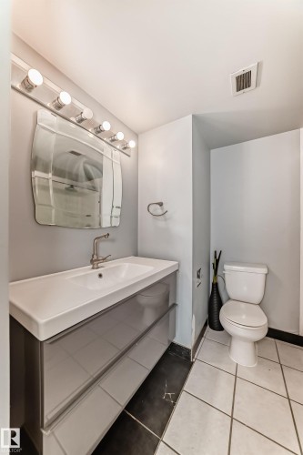 Modern vanity with integrated sink, sleek wall-mounted mirror, and contemporary lighting fixture - 405 10135 Saskatchewan Drive Nw, Edmonton, AB - Indoor Photo Showing Bathroom