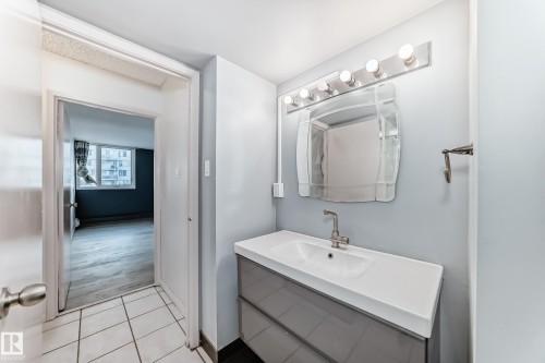 Bathroom vanity featuring a white integrated sink, chrome faucet, and mirrored light fixture - 405 10135 Saskatchewan Drive Nw, Edmonton, AB - Indoor Photo Showing Bathroom