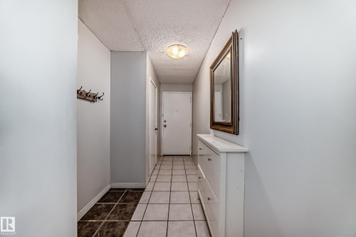 Entryway featuring light-toned square tile flooring, a built-in wall-mounted coat rack, and a flush-mount ceiling light fixture - 405 10135 Saskatchewan Drive Nw, Edmonton, AB - Indoor