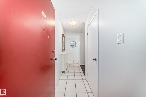 Entryway featuring a red main door, white square floor tiles, and a ceiling-mounted light fixture - 405 10135 Saskatchewan Drive Nw, Edmonton, AB - Indoor Photo Showing Other Room