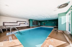 Indoor swimming pool featuring a light blue tiled basin with metal grab rails - 