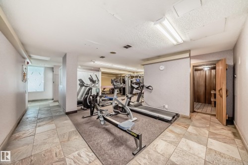 Dedicated fitness area featuring exercise equipment, textured wall finishes, and overhead fluorescent lighting - 405 10135 Saskatchewan Drive Nw, Edmonton, AB - Indoor Photo Showing Gym Room