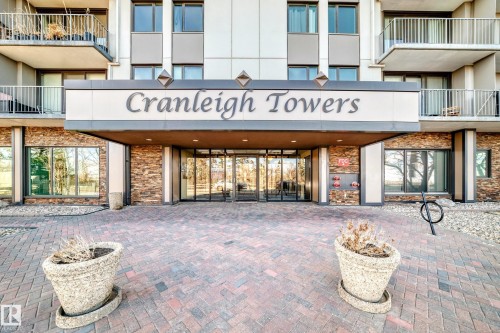 "Cranleigh Towers" building entrance featuring a brick paver walkway, stacked stone facade accents, glass double entry doors, and upper-level balconies with metal railings - 405 10135 Saskatchewan Drive Nw, Edmonton, AB - Outdoor