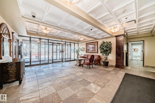 Spacious lobby featuring large format tile flooring, a coffered ceiling with decorative lighting, and a wall of glass doors providing abundant natural light - 405 10135 Saskatchewan Drive Nw, Edmonton, AB - Indoor Photo Showing Other Room