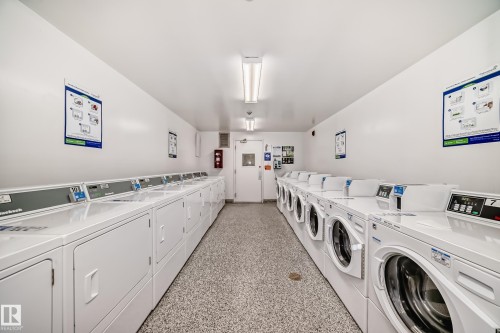 Dedicated laundry facility featuring multiple front-loading and top-loading machines, fluorescent overhead lighting, and durable speckled flooring - 405 10135 Saskatchewan Drive Nw, Edmonton, AB - Indoor Photo Showing Laundry Room