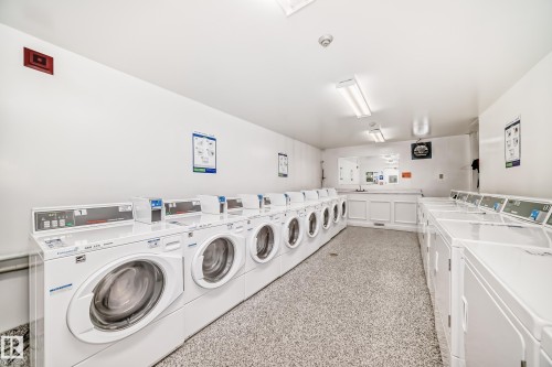 On-site laundry facility featuring multiple front-loading washers and top-loading dryers - 405 10135 Saskatchewan Drive Nw, Edmonton, AB - Indoor Photo Showing Laundry Room