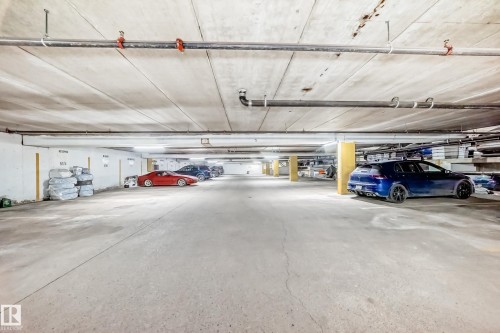 Underground parking garage featuring concrete flooring, exposed ceiling utilities, and designated parking spaces - 405 10135 Saskatchewan Drive Nw, Edmonton, AB - Indoor Photo Showing Garage